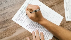 Hände füllen ein amtliches Antragsformular am Tisch aus