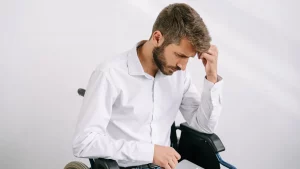 Junger Mann im Rollstuhl arbeitet zu Hause am Laptop