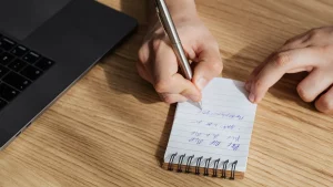 Person trägt handschriftlich Notizen in ein Heft ein