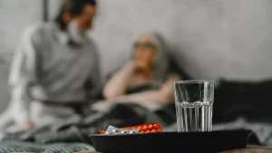 Tablett mit Medikamenten und einem Glas Wasser neben dem Pflegebett