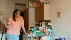 Seniorin und Betreuungskraft sitzen gemeinsam am Küchentisch in der Wohnung