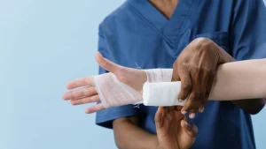 Pflegefachkraft wechselt zu Hause den Verband bei einer Patientin