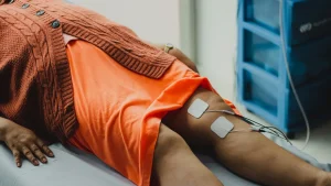 Physiotherapeutin mobilisiert einen Patienten im Krankenhausbett nach Intensivbehandlung